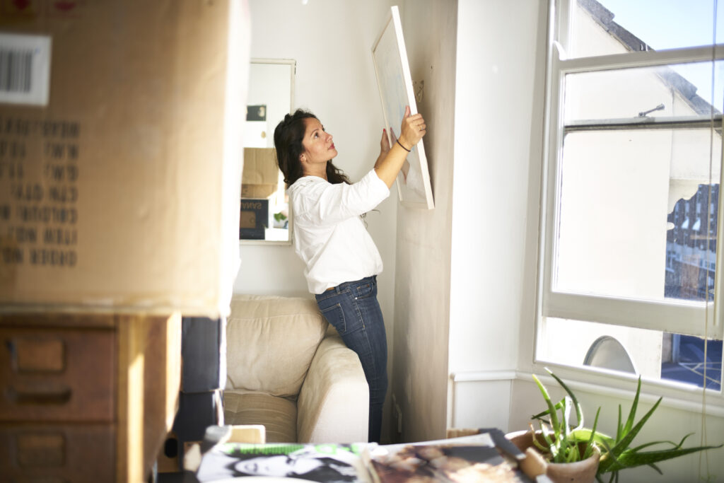 Une femme décroche un tableau du mur pour l'emballer en vue de son déménagement