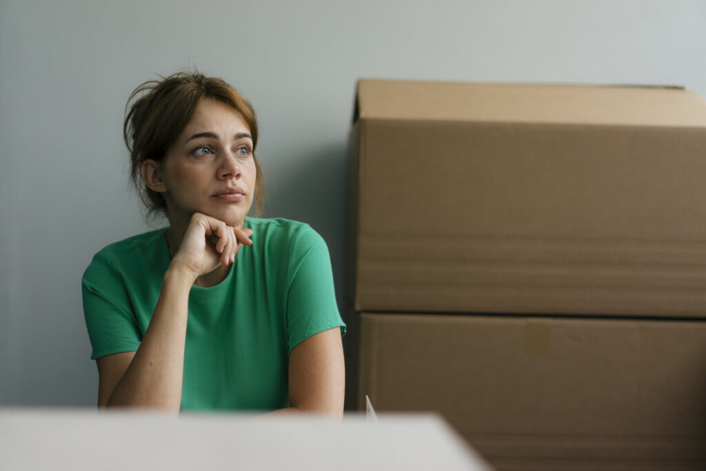 Une femme pensive près de cartons dans un bureau