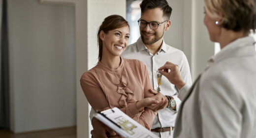 Un couple heureux achète une nouvelle maison et reçoit les clés des mains de l'agent immobilier.
