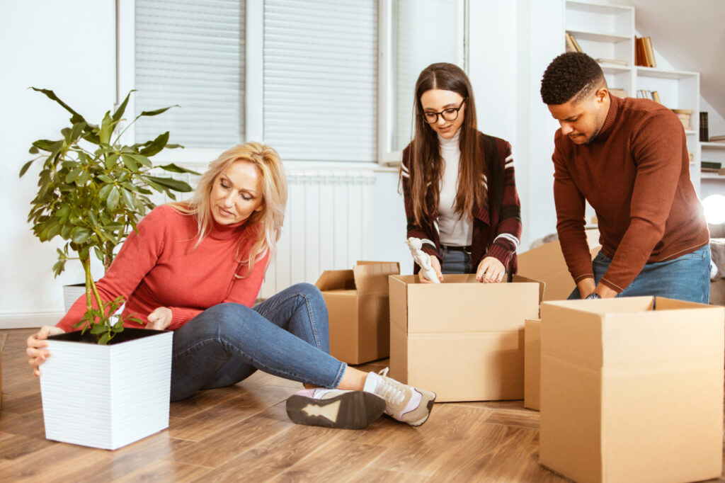 Packing various things and in boxes during moving to another apartment. Relocation. Multi-ethnic and multi-racial group of people.
