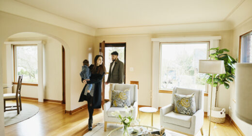 Wide shot of family with toddler walking though front door into living room of home for sale during open house