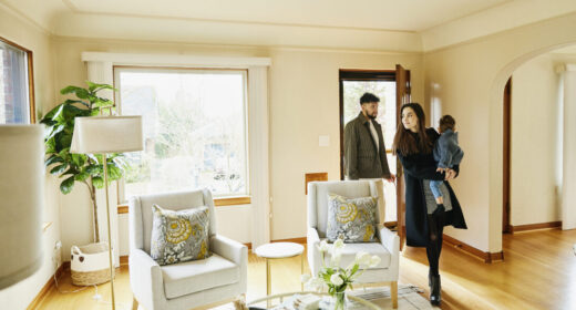 Wide shot of family with toddler walking though front door into living room of home for sale during open house